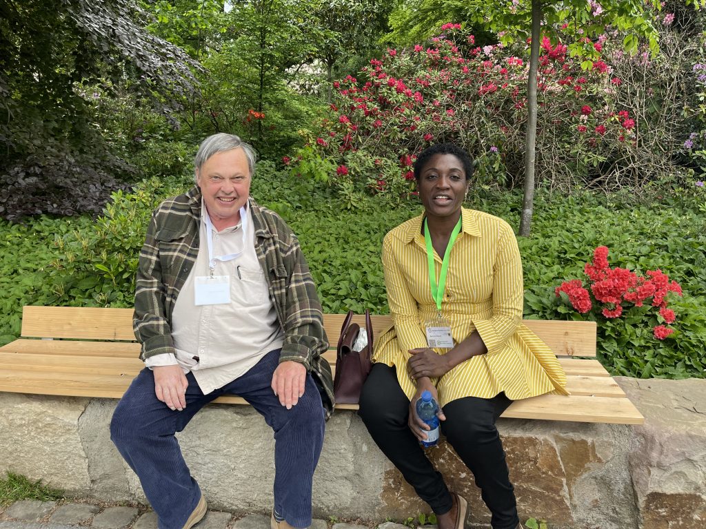 Two people sitting on a bench in a garden.