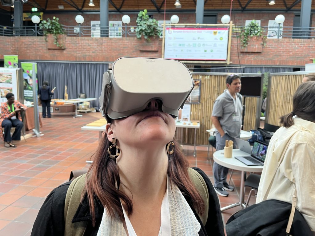 A person with a VR headset over their eyes, looking up in a large conference room.